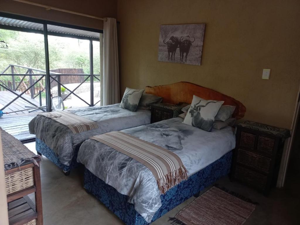 Duas camas num quarto com uma janela em Kichaka Nyumba em Marloth Park