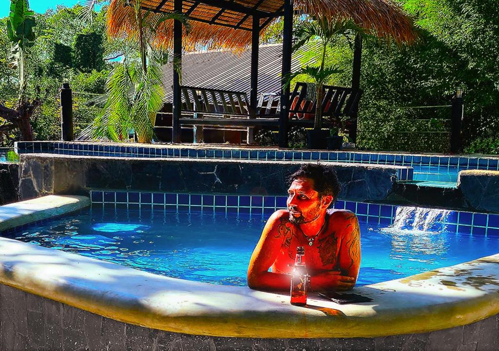 a man sitting in a swimming pool with a drink at Jungle Fever Koh Chang in Ko Chang
