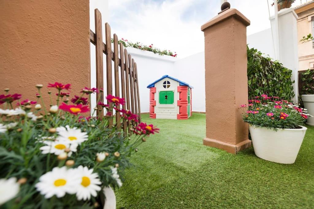 un jardín con flores y una casa de juegos en Family Century House with terrace and parking, en Valencia