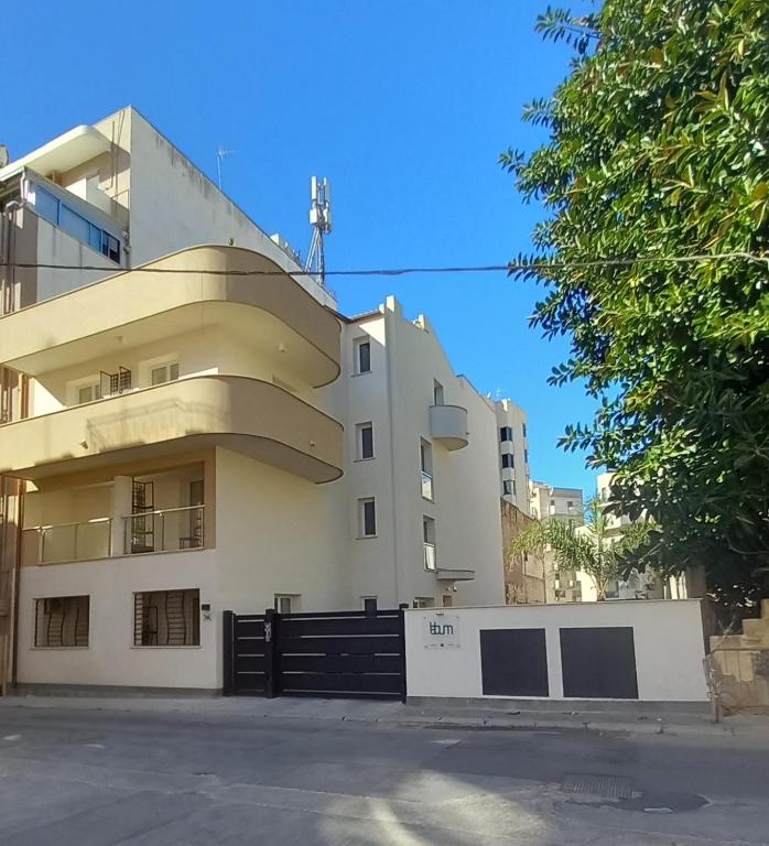 a white building with a black fence in front of it at Lebum Apartments & Suites in Marsala