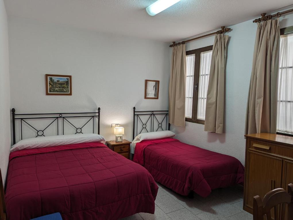 グラナダにあるPensión Ciudad Navarro Ramosのベッド2台 赤いシーツ&窓が備わるドミトリールームのベッド1台分です。