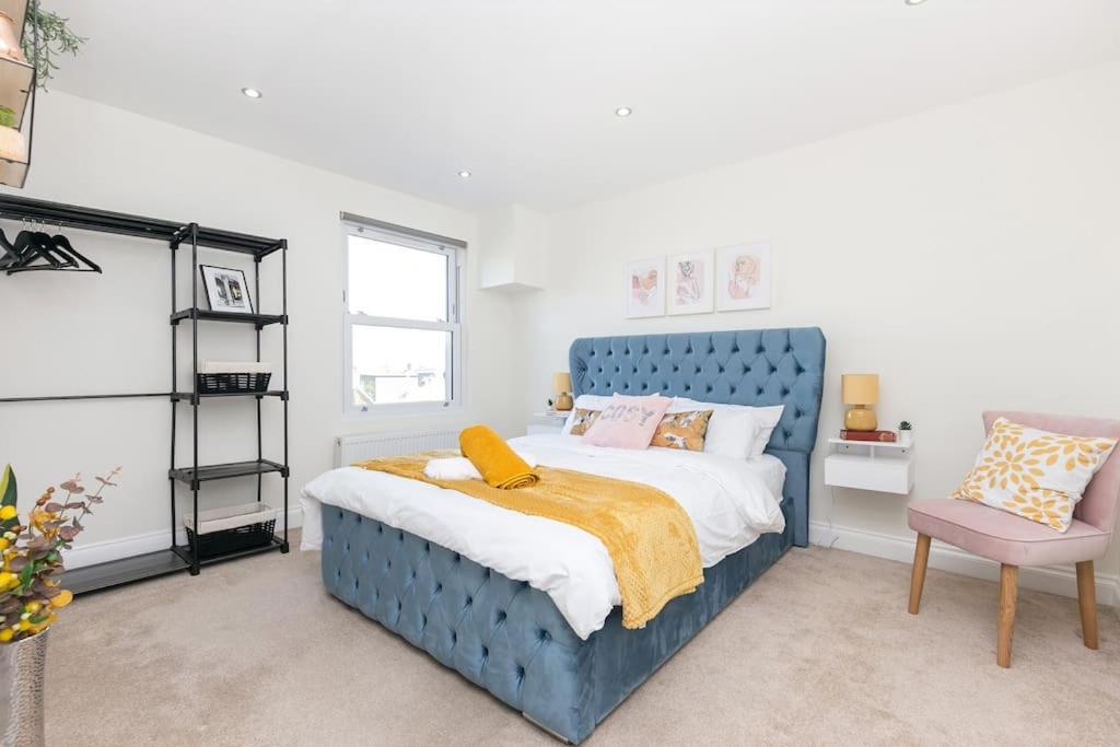 1 dormitorio con 1 cama azul y 1 silla en Stunning S/Wimbledon Flat w/parking in London, Uk, en Londres