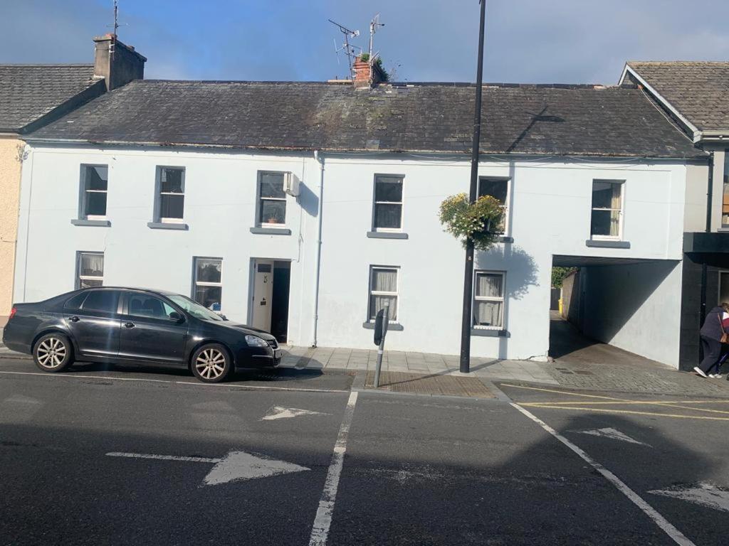 a black car parked in front of a white building at Kickham Street Budget Accommodation in Carrick-on-Suir
