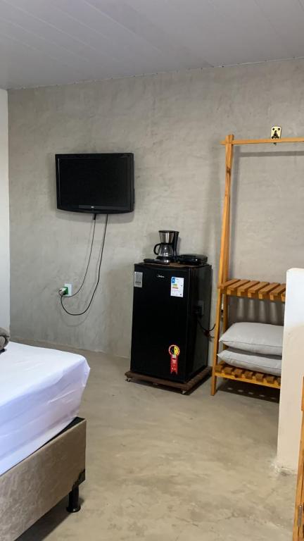 um quarto com uma cama e uma televisão na parede em Chalé das flores lírio em São Miguel do Gostoso