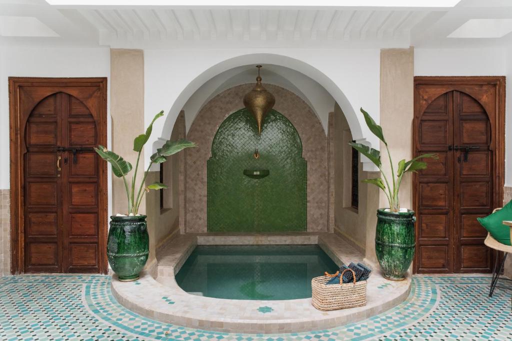 a swimming pool in a room with two plants at Riad of the Moon in Marrakesh