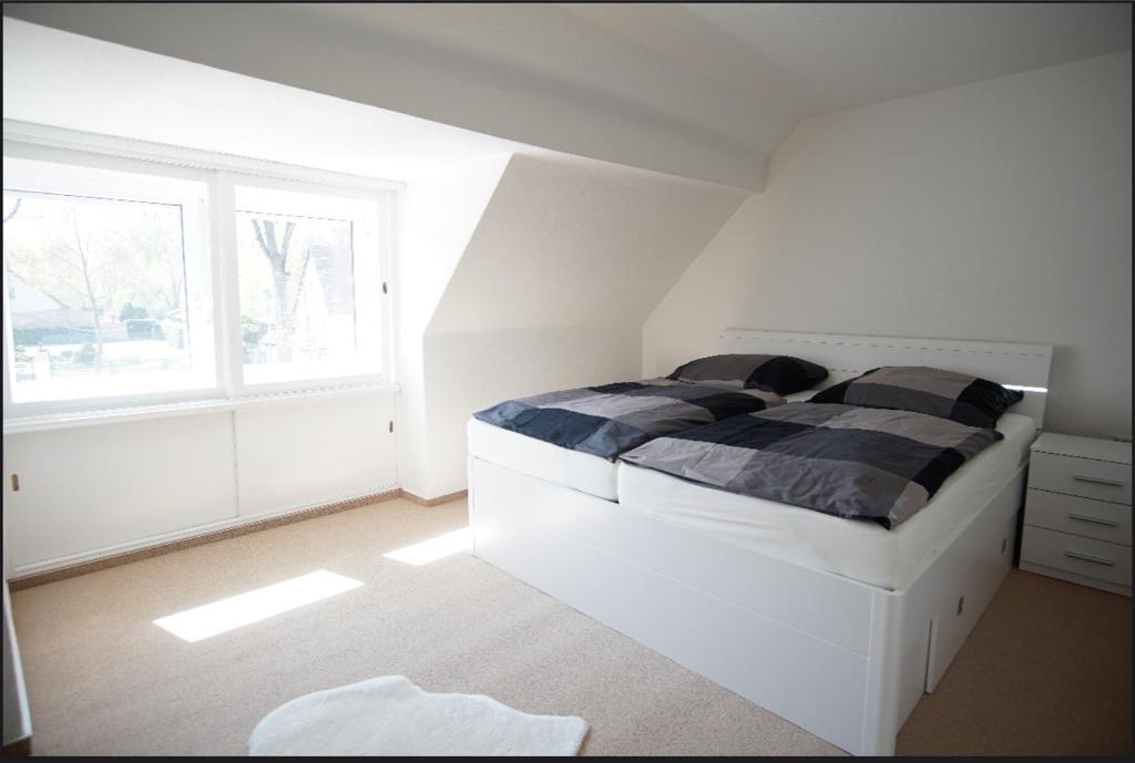 a white bedroom with a bed and a window at Haus am See in Schwielowsee