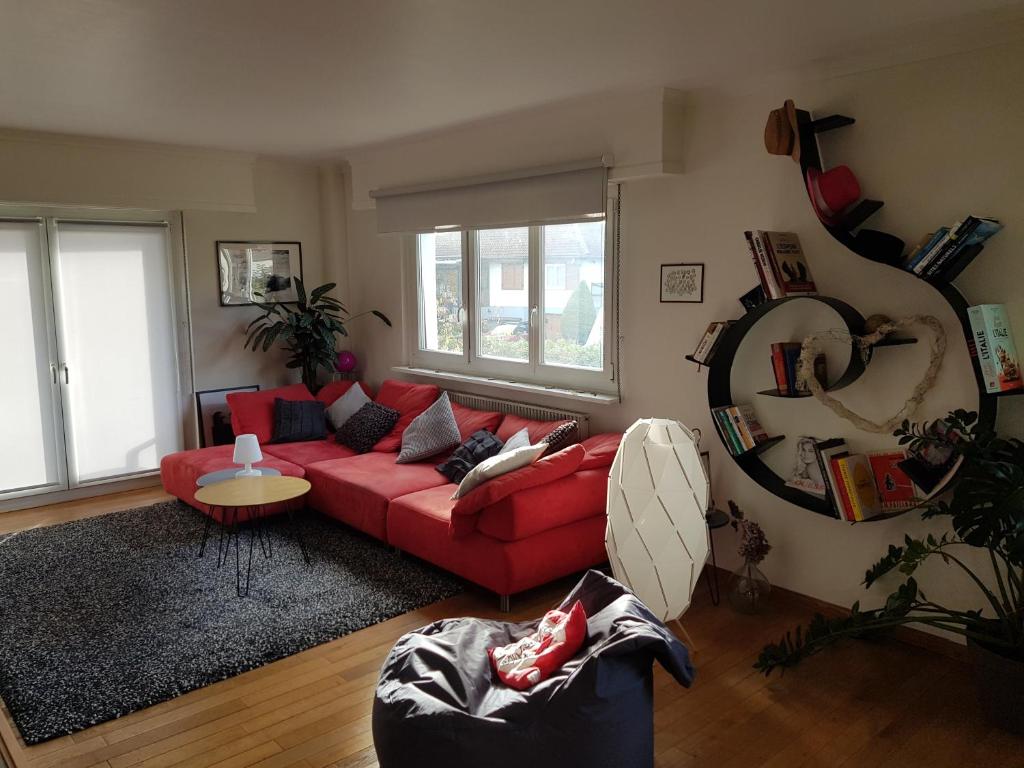 uma sala de estar com um sofá vermelho e uma mesa em Joli appartement calme et spacieux, proche Strasbourg em Duppigheim