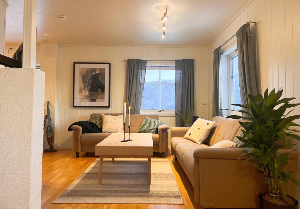 uma sala de estar com um sofá e uma mesa em Koselig leilighet med fantastisk utsikt em Tromsø