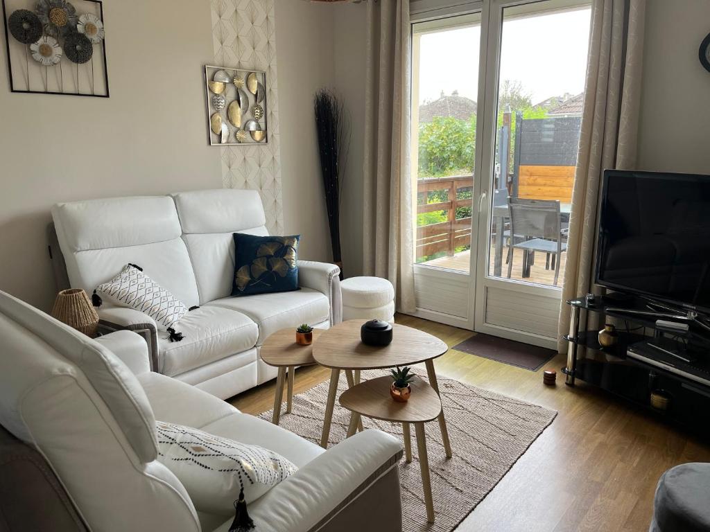 un salon avec un canapé blanc et une télévision dans l'établissement Maison à 700m de la plage, à Courseulles-sur-Mer