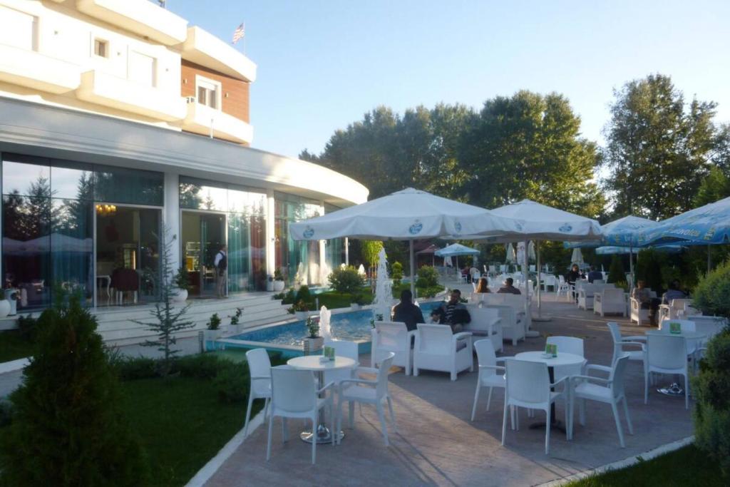 a restaurant with white tables and chairs and umbrellas at Apple Red Hotel in Fier