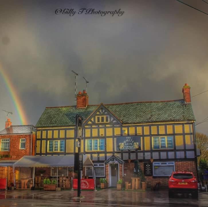 um edifício amarelo e preto com um arco-íris ao fundo em The White Lion Inn em Brinklow