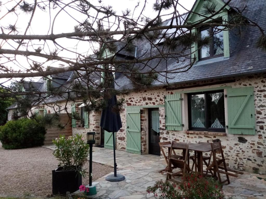 una casa con puertas verdes y una mesa frente a ella en Chambre d hote La Roussiere en Saint-Ouen-des-Toits