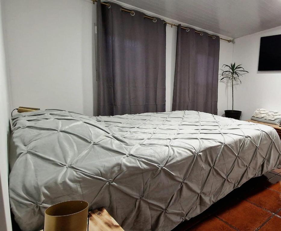a bedroom with a bed covered in a silver comforter at AL - Studio to Travelers in Ponta Delgada