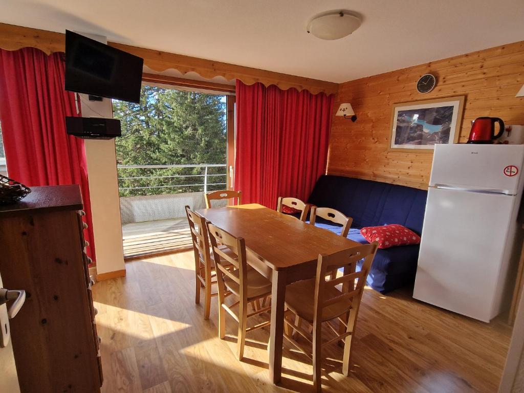 une cuisine et une salle à manger avec une table et un réfrigérateur dans l'établissement Appartement au pied des pistes et du park nordique, à Chamrousse