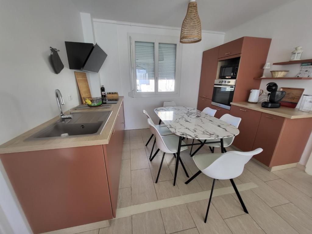 cocina y comedor con mesa y sillas en Bienvenue chez ANOUK en Châlons-en-Champagne