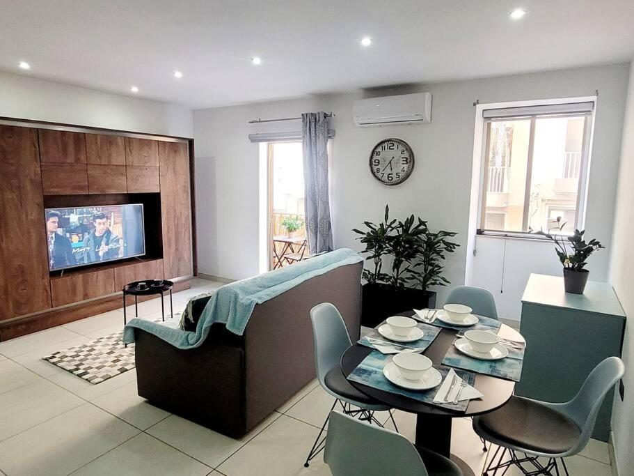 uma sala de estar com uma mesa e um sofá em New&Cosy Apartment with Balcony em San Ġwann