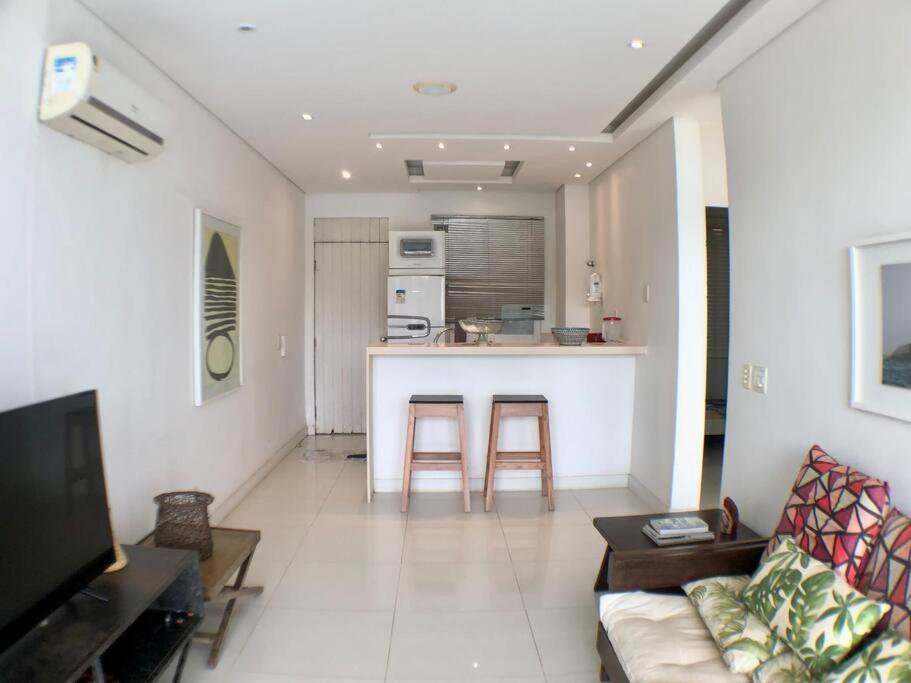 a living room with a couch and a kitchen at Lindo Flat praia deserta búzios in Armacao dos Buzios