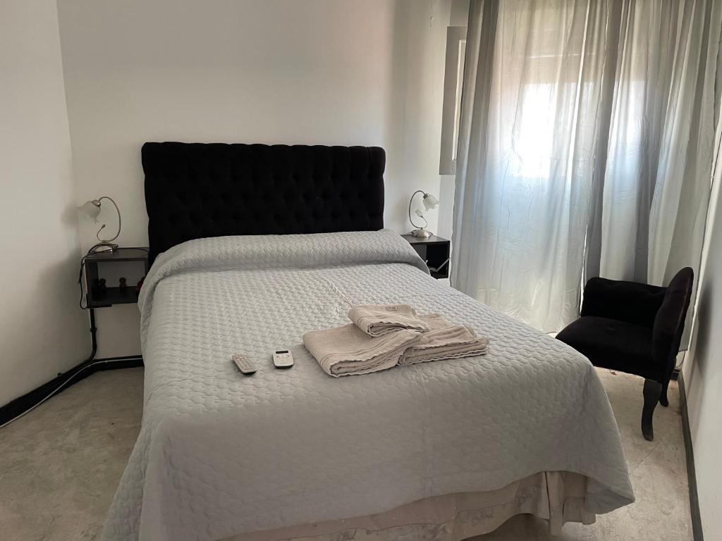 een slaapkamer met een bed met een badjas en een stoel bij Valentino in Termas de Río Hondo