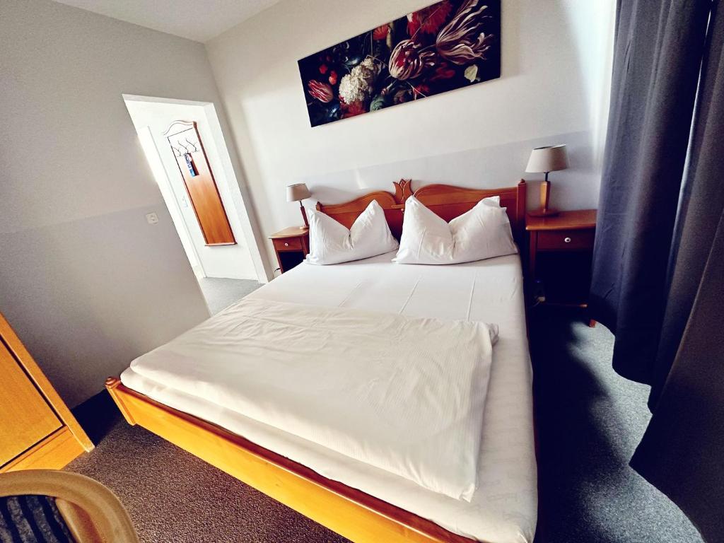 a bedroom with a bed with white sheets and pillows at Hotel Rheinfall in Neuhausen am Rheinfall