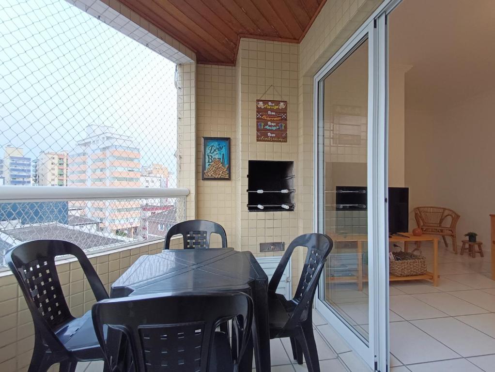 a dining room with a table and chairs and a balcony at Apê com churrasqueira guilhermina in Praia Grande