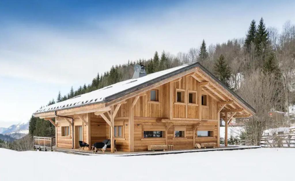 Cabaña de madera grande con techo cubierto de nieve en Coco Chalet en Arâches-la-Frasse