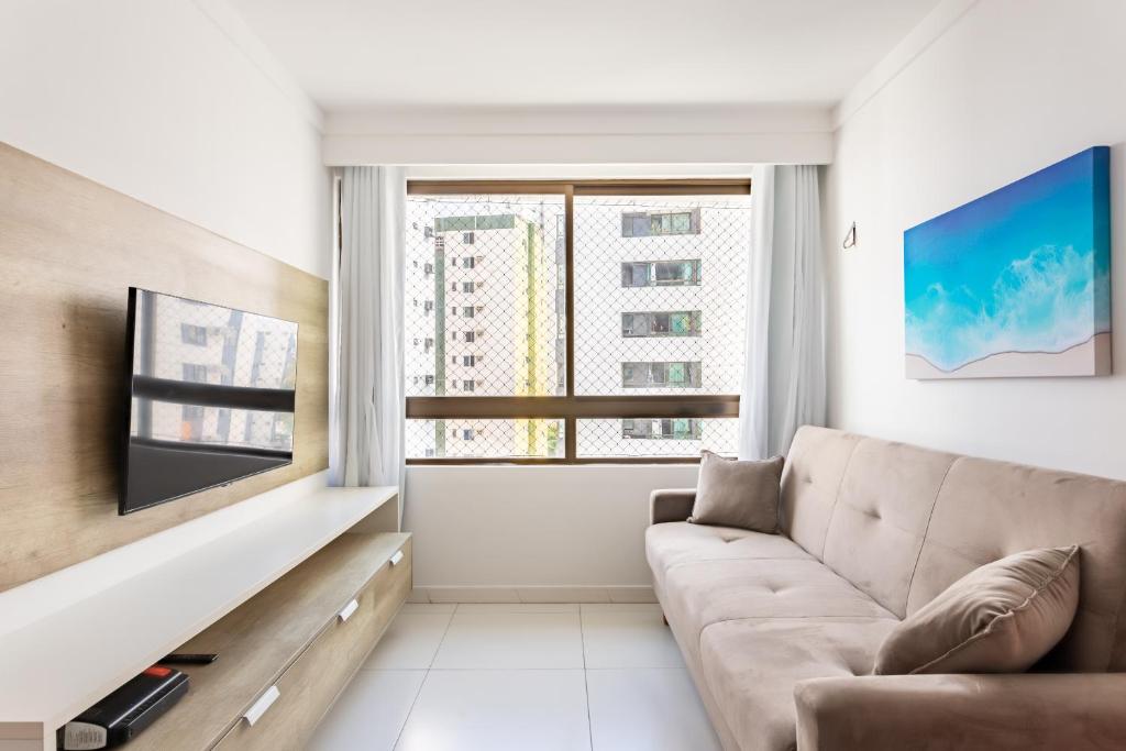 uma sala de estar com um sofá e uma grande janela em Flat 701 - PortoMar Home Club no Recife