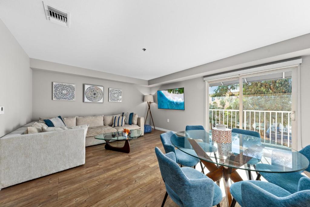 uma sala de estar com uma mesa de vidro e cadeiras azuis em Exquisite Ocean View 2-Story Haven Top floor em Los Angeles