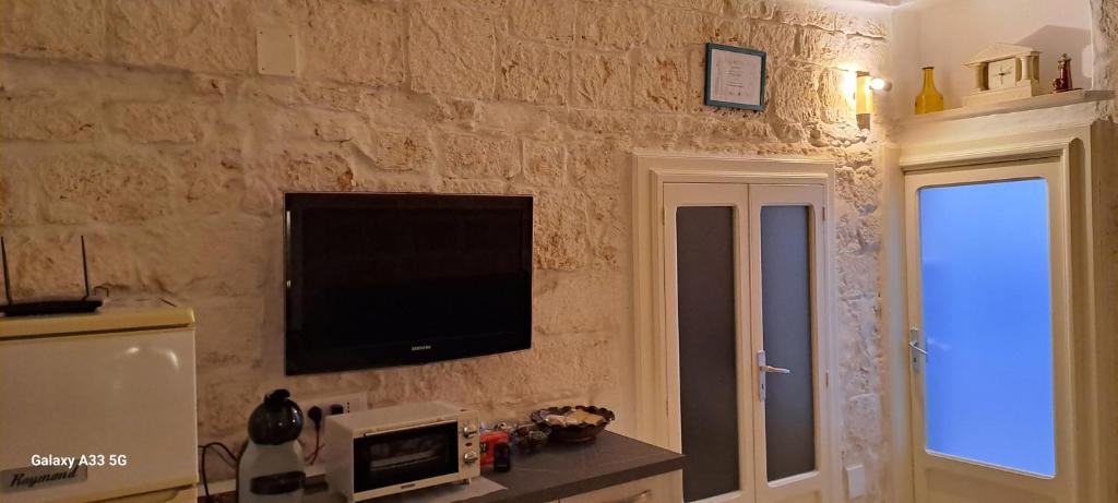 salon z telewizorem na kamiennej ścianie w obiekcie La Casuccia w mieście Ostuni