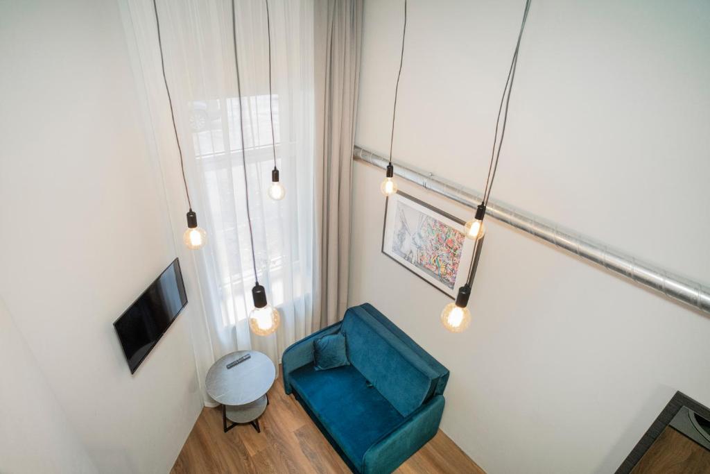Zimmer mit einem blauen Stuhl und einem TV in der Unterkunft Teeny Tiny Lofts in Center in Kaunas