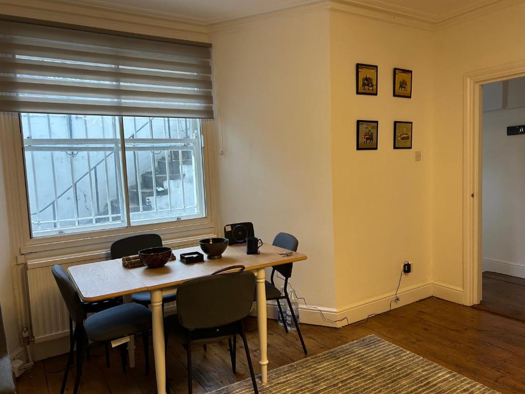 uma sala de jantar com uma mesa e cadeiras e uma janela em West Kensington em Londres