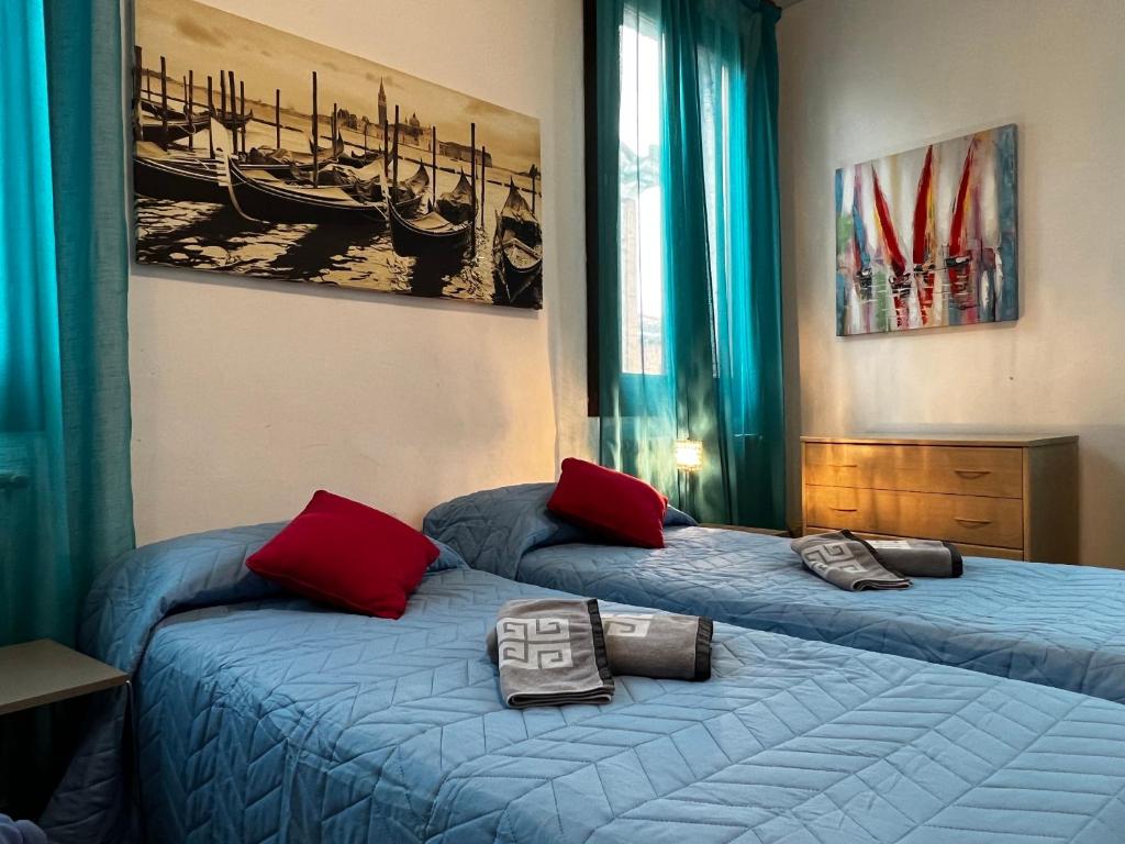 two beds in a room with blue sheets and red pillows at TINTORETTO 1 CON TERRAZZA SOPRA IL TETTO, 3 bagni, 3 grandi camere da letto, SUPER NUOVO in Venice