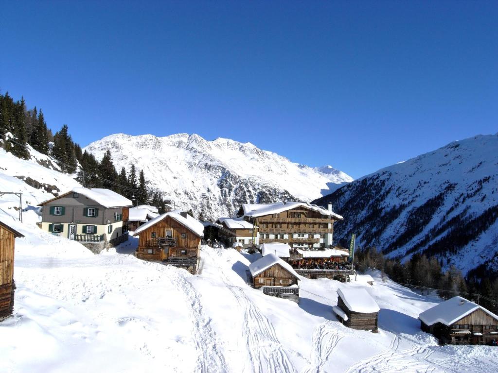 un village recouvert de neige avec une montagne en arrière-plan dans l'établissement Hotel Silbertal - Almhütten, à Sölden