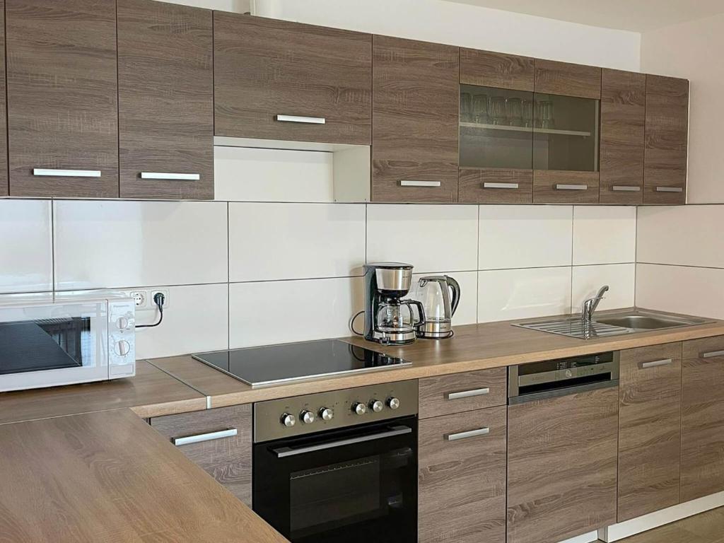 a kitchen with wooden cabinets and a sink and a microwave at T&K Apartments - Wegberg - 3-6 Zimmer Apartments in Wegberg