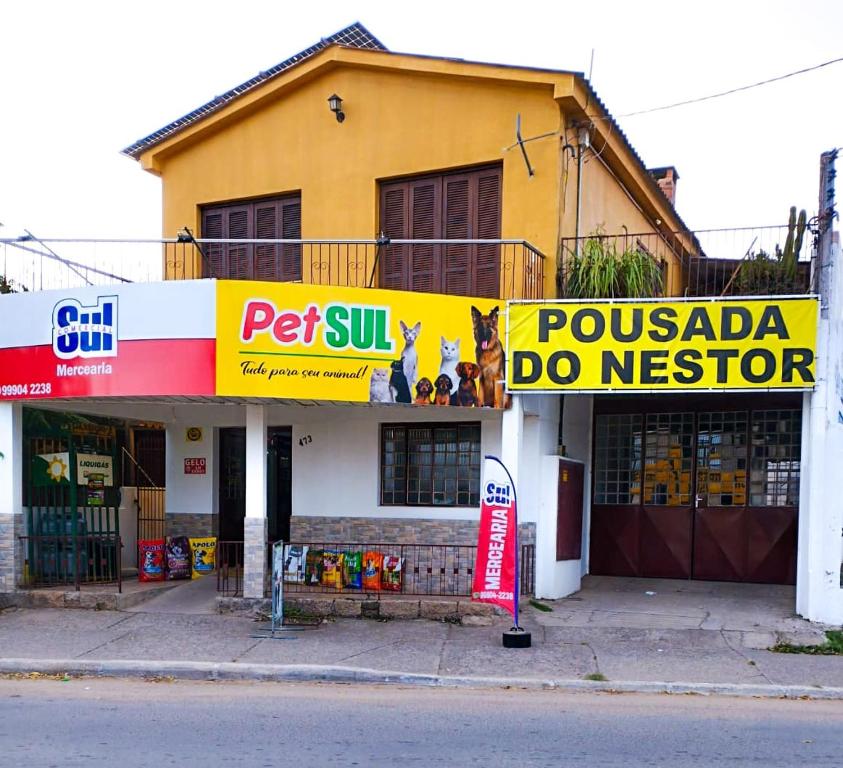 un edificio amarillo con un cartel delante en Pousada do Nestor, en São Gabriel