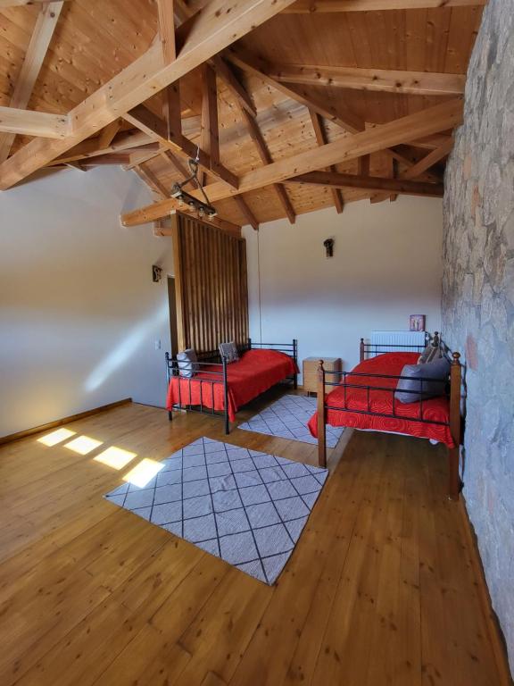 a room with two red beds and a stone wall at Τα πέτρινα στο Σκεπαστό in Kalavrita