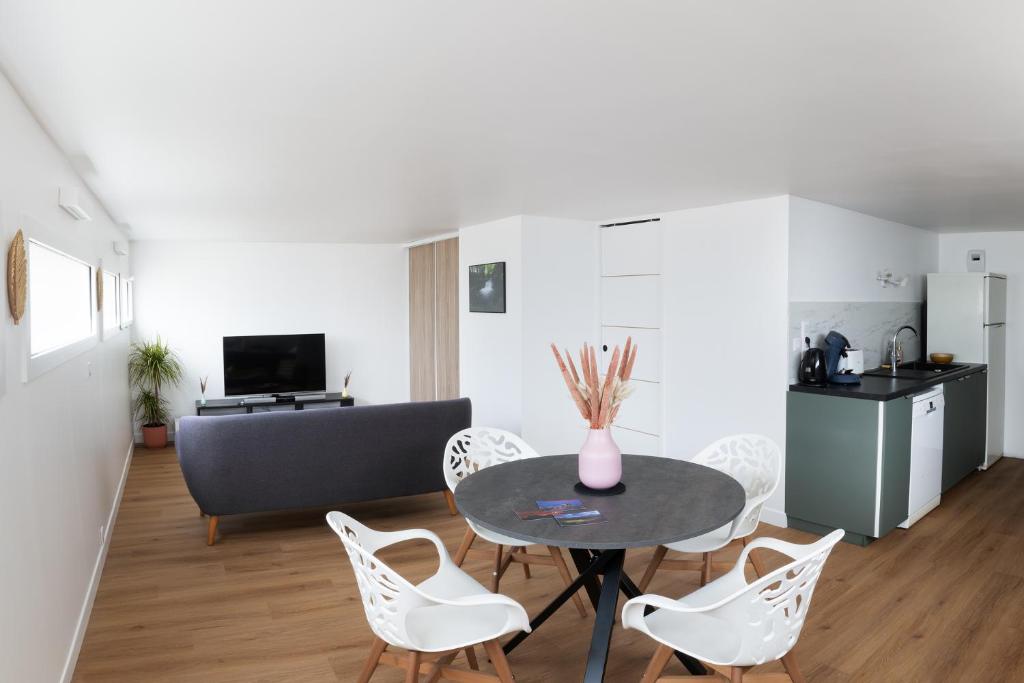 - un salon avec une table et des chaises blanches dans l'établissement Charmant appartement proche de Clermont-Ferrand, à Châteaugay