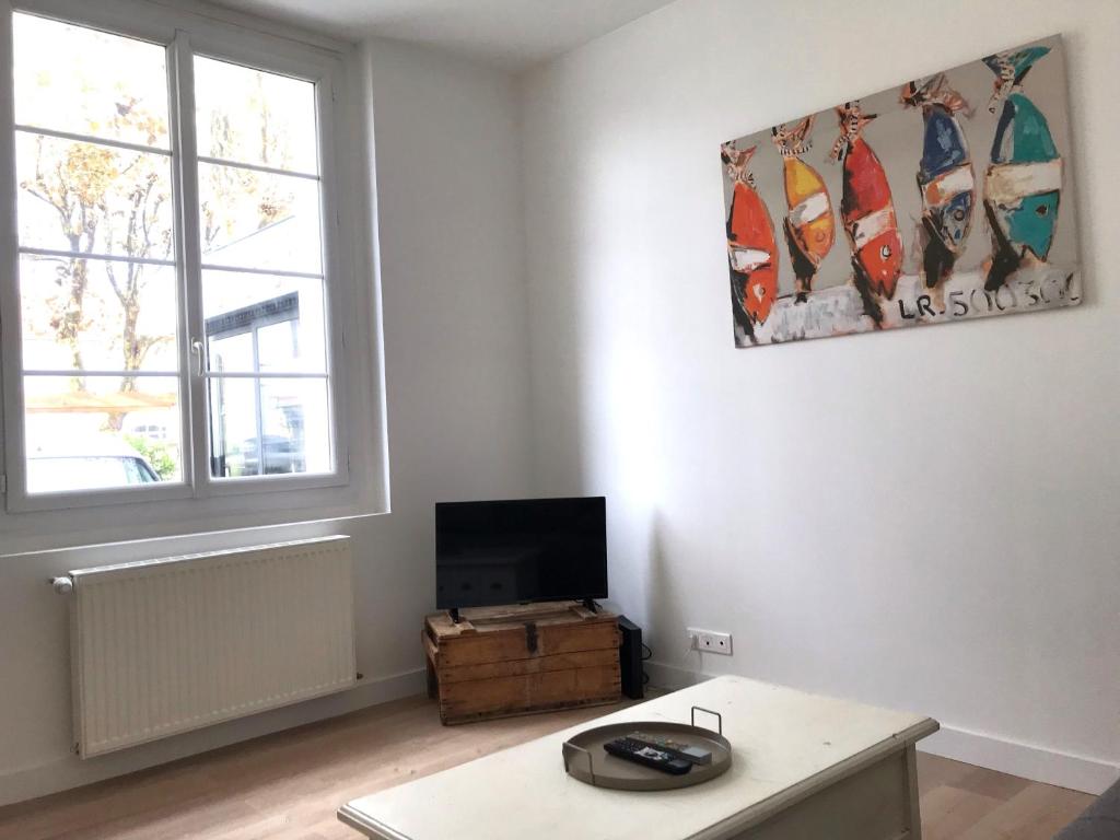 a living room with a table and a tv at Maison de vacances in Châtelaillon-Plage