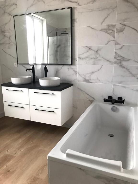 a white bathroom with a tub and a sink at Maison de vacances in Châtelaillon-Plage