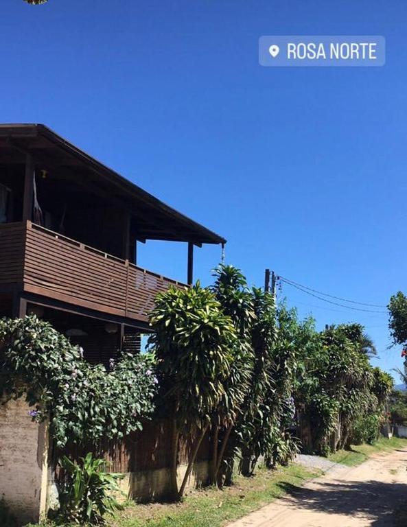 a house with a row of trees next to a road at Casas Paz e Amor Praia do Rosa Sunset e Sunrise in Imbituba