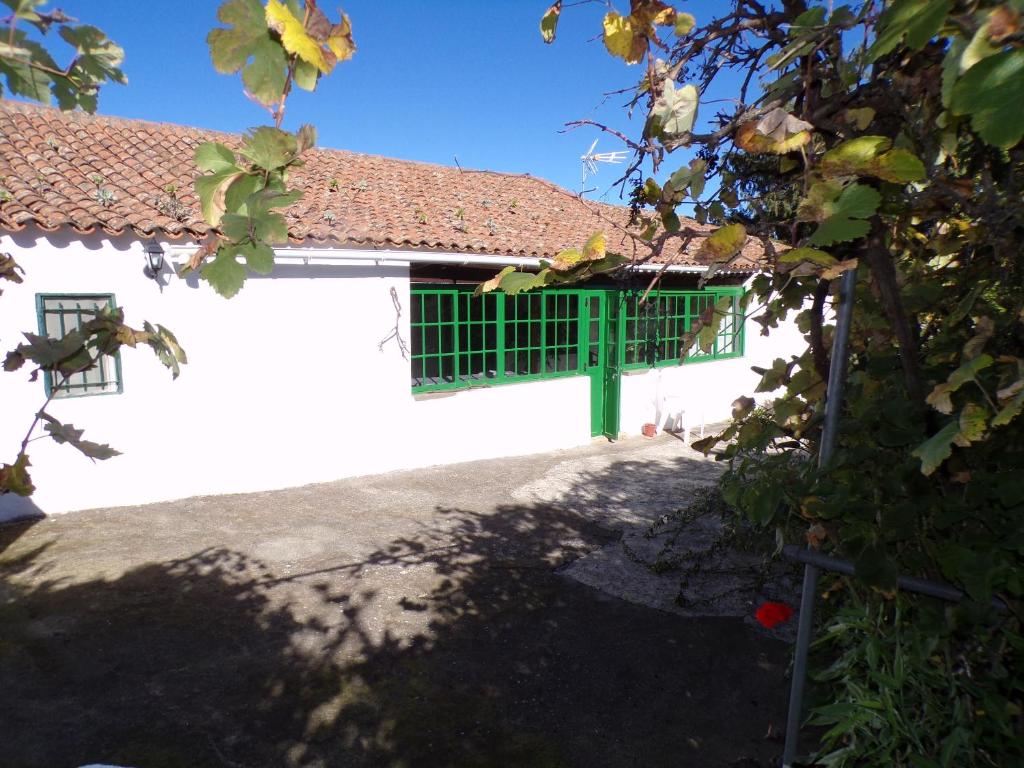 a white building with a green window and a tree at CASA DIEGUITO, TURISMO RURAL in Valleseco