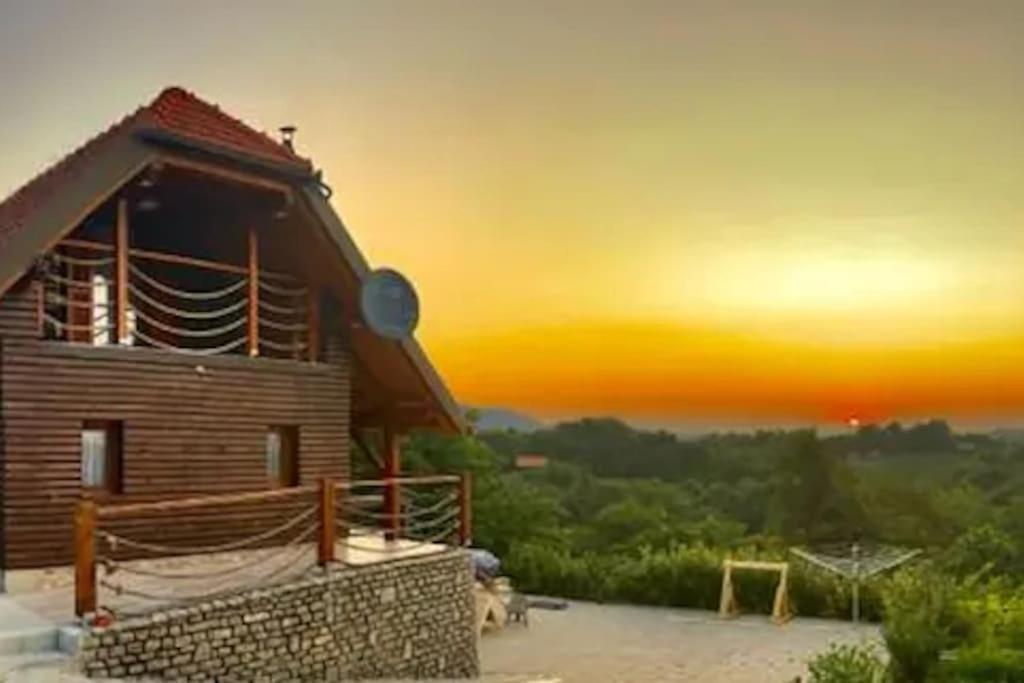 une maison en bois avec un coucher de soleil en arrière-plan dans l'établissement Country Lodge, à Brežice