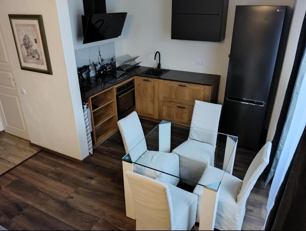 cocina con mesa de cristal y sillas blancas en Suur-Aia 21 Apartment en Paide