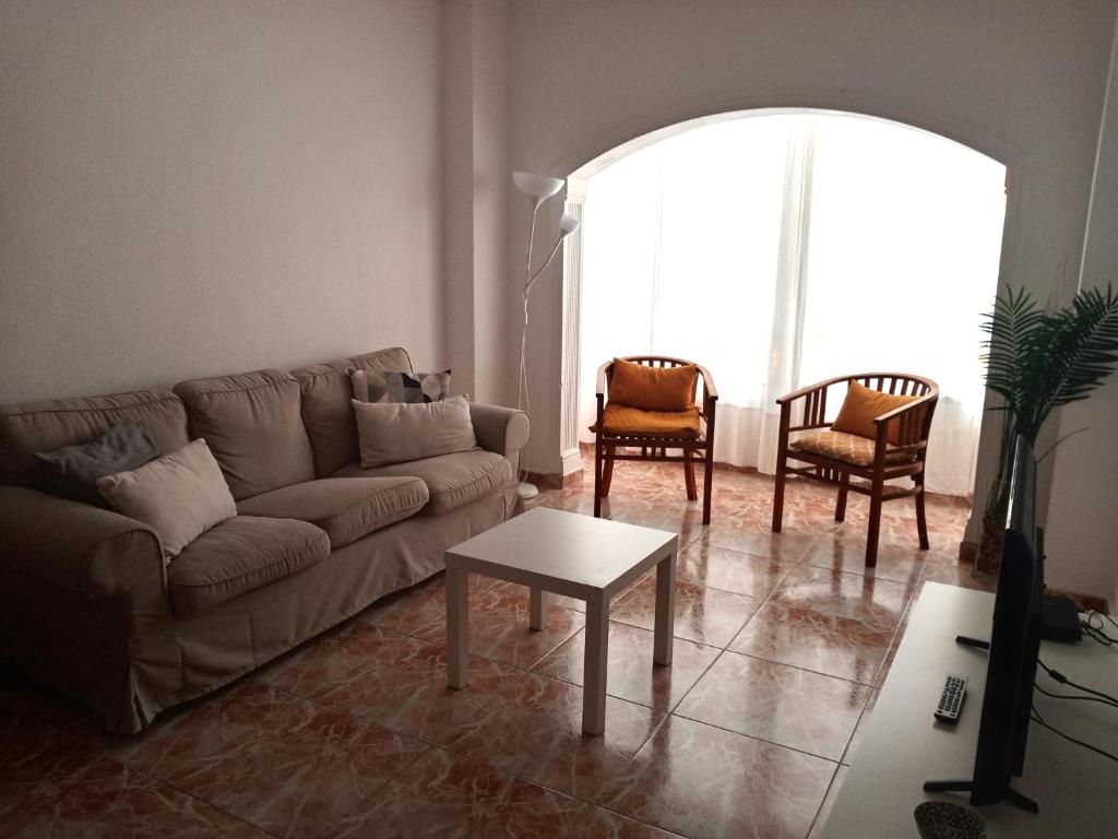 ラスパルマス・デ・グランカナリアにあるAmplio apartamento a 50 metros de la Playaのリビングルーム(ソファ、椅子2脚、テーブル付)