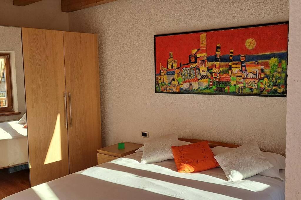 1 dormitorio con 1 cama y una pintura en la pared en In cima alla contrada en Pieve di Cadore