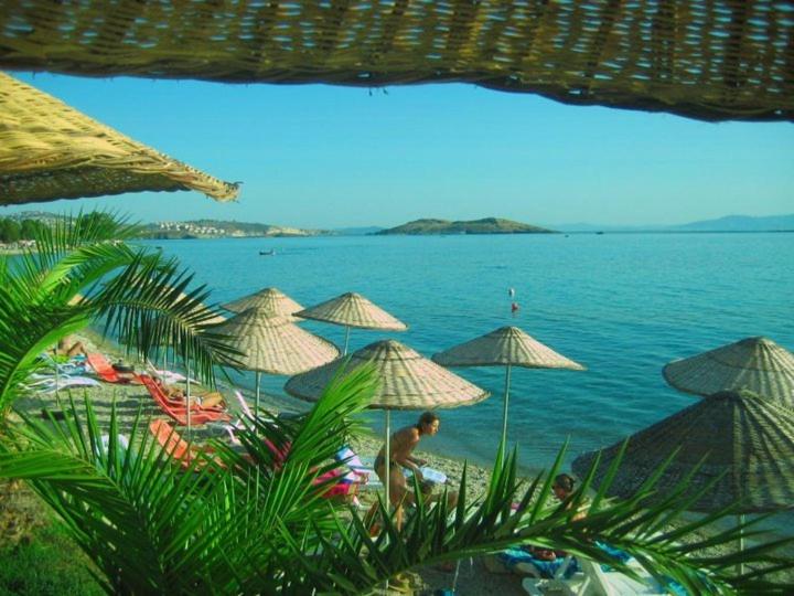 un homme debout sur une plage avec des parasols dans l'établissement Teras Motel, à Foça