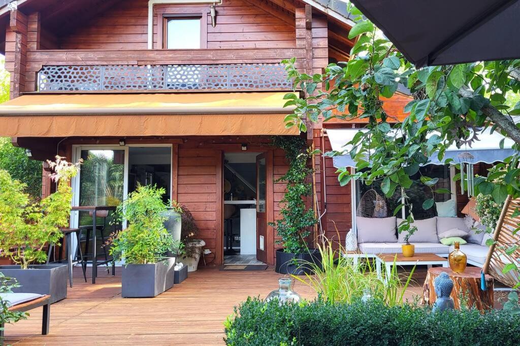 una casa con una terraza de madera con sillas y plantas en Dans un parc privatif arboré, en Réau