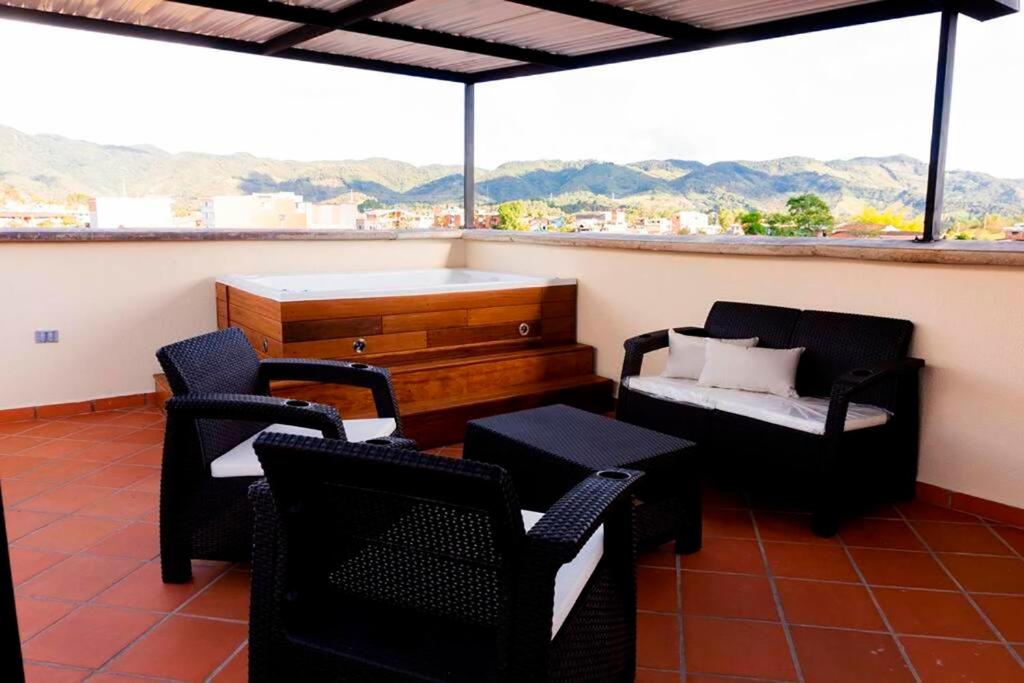 einen Balkon mit Stühlen, einem Bett und einem Fenster in der Unterkunft Apartamento 402 - Terraza con Jacuzzi - 3 Habitaciones - Rentas Cortas Gerencial in Guatapé