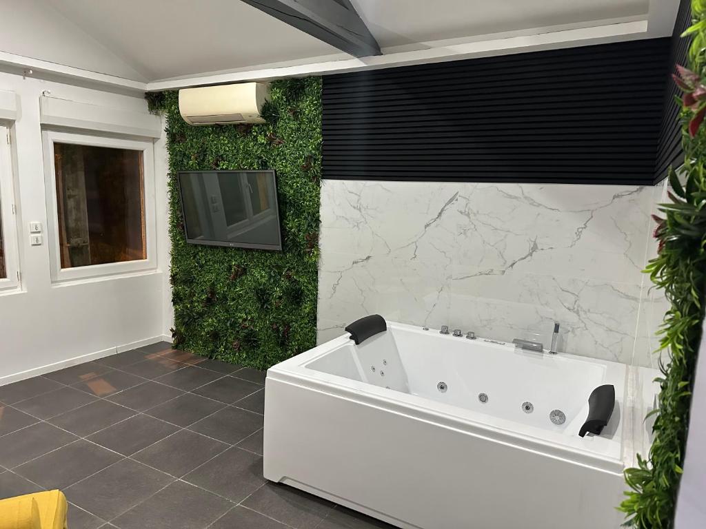 ein Badezimmer mit einer weißen Badewanne und einem TV an der Wand in der Unterkunft Love room borabora 6 in Trévoux