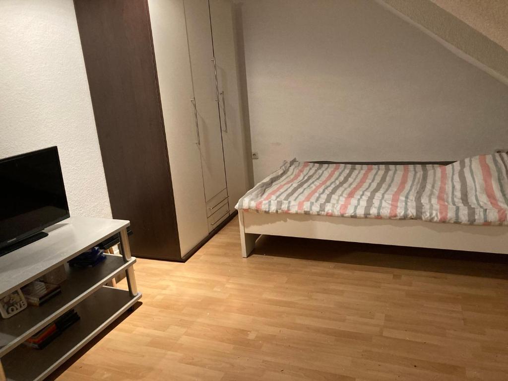 Schöne Dachgeschosswohnung في إيسن: غرفة نوم مع سرير وخزانة مع تلفزيون