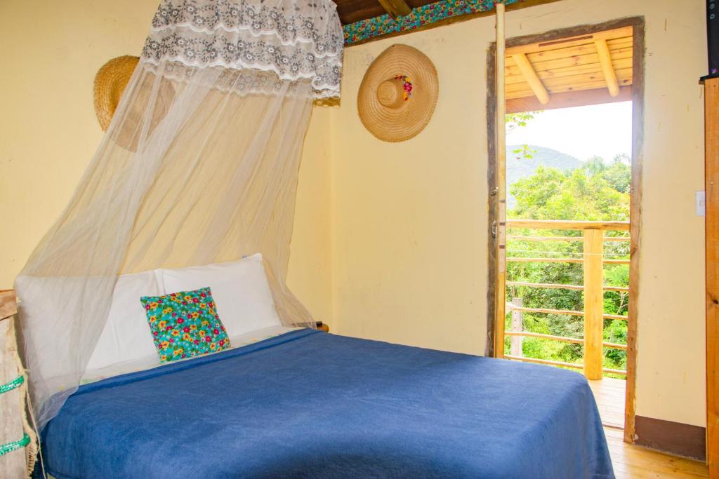 a bedroom with a blue bed with a window at Mini Chalés Madeira Beach in Ubatuba